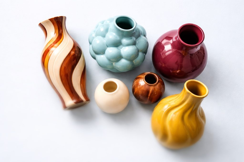Bild på vaser i keramik, i olika färger och former. Brun-gul-beige-randing, bubblig ljusblå, glad vinröd, gul. Mjuka och böljande färger.